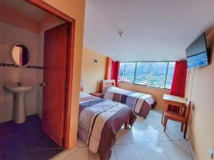 two beds in a room with a sink and a window at Hostal Huagancu in Huari