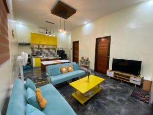 a living room with a blue couch and a tv at Kia Ora Villa Staycation in Los Baños
