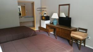 a hotel room with a bedroom with a bed and a television at Coach Stop Motel in Wellsboro