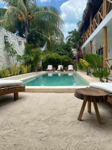 a swimming pool with two benches in front of a building at Casa Baloo in El Cuyo +18 photos