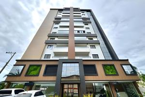 a tall building with cars parked in front of it at Harmonie apto requintado | Centro | 200m do mar in Itapoa