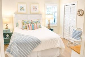 a bedroom with a white bed with pillows and a chair at Bright Coastal Condo in Saint Simons Island +20 photos