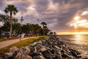 a beach with a lighthouse and palm trees and the ocean at Bright Coastal Condo in Saint Simons Island