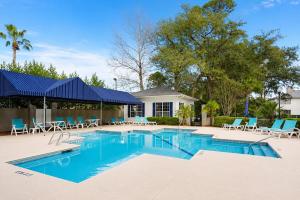 a swimming pool with chairs and a house at Bright Coastal Condo in Saint Simons Island