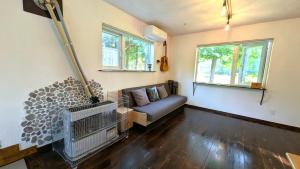 a living room with a couch and two windows at 暮らす宿ソラプチ Sorapchi Cabin in Ochiai
