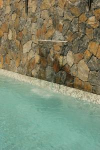 a pool of blue water next to a stone wall at Hotel Boutique Kasa Sara in San Patricio Melaque