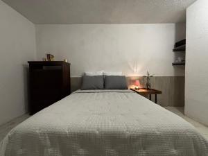 a bedroom with a bed with a white bedspread and a table at Casa Cantera in Tequisquiapan
