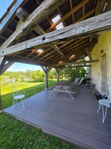 a wooden deck with chairs and tables under a roof at Gîte L' authentique in Saint-Germain-des-Bois