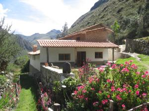 a house in the mountains with flowers in front of it at Hospedaje Illariy in Yanama
