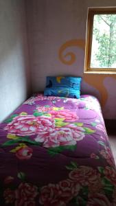 Una cama con una manta púrpura con flores. en Hospedaje Illariy, en Yanama