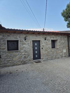 a stone house with a black door and two windows at Casa da Mexieira em Ponte da Barca in Ponte da Barca