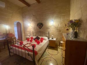 a bedroom with a bed with red flowers on it at Barumbara Farmhouse in Sannat +43 photos