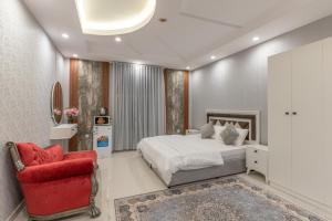 a bedroom with a bed and a red chair at Jeddah Apartment in Jeddah