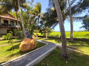 a statue sitting on top of a rock next to a road at Village Mango Resort Yala in Tissamaharama