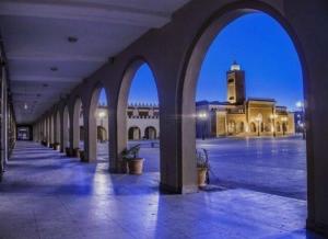 an empty courtyard with a large building with a clock tower at Villa Sereine in Sidi Yahia