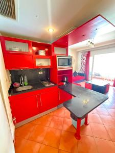 a kitchen with red cabinets and a table in it at Porto Sokhna Aprtment Pool View - MR in Ain Sokhna