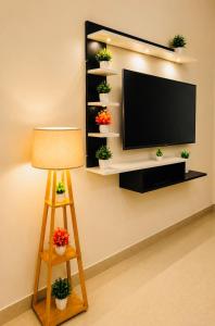 a flat screen tv on a wall with potted plants at Moonleaf Stay, Guwahati in Guwahati