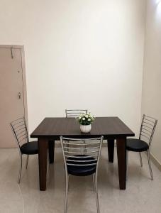 a wooden table with chairs and a vase with flowers on it at Moonleaf Stay, Guwahati in Guwahati +10 photos