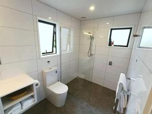 a white bathroom with a toilet and a shower at Kerigold Secluded Chalets Motel in Kerikeri +25 photos