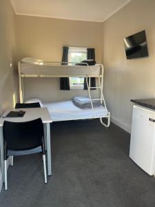 a small room with a bunk bed and a desk at Stratford Motel & Holiday Park in Stratford