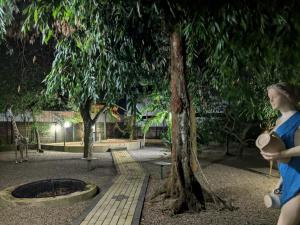 a woman standing next to a tree in a park at Prince Cottage - Entire Private Cottage in Kesbewa +7 photos