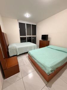 a bedroom with two beds and a television in it at The Hilltop Apartment in Guadalajara +35 photos