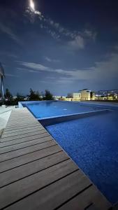 a large swimming pool with blue water and a wooden deck at The Hilltop Apartment in Guadalajara