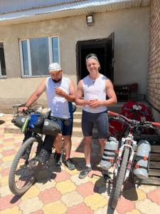 two men are standing next to their bikes at Adventure Guest House in Pokrovka