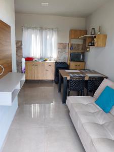 a kitchen and living room with a couch and a table at Morada dos eucaliptos in Capão da Canoa