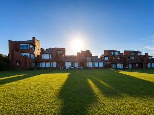 a large brick building with the sun in the background at Despertá frente al mar! Loft con bajada privada! in Santa Clara del Mar