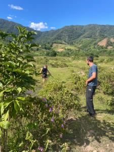 two men are standing in a field with plants at Aluoi Homestay in Hue