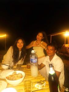 a group of people sitting around a table with food at Aluoi Homestay in Hue