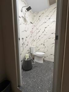 a bathroom with a toilet and a marble wall at Gassania Hostel in Banda Aceh