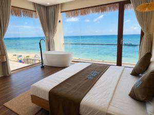 a bedroom with a large bed with a view of the ocean at Sala Beach Villa Phú Quý in Cù Lao Thu