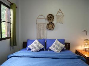 a bed with blue sheets and pillows in a bedroom at นากลางดอย Naklangdoi in Ban Na Kham
