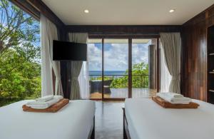 two beds in a room with a view of the ocean at Tanote Villa resort, Koh-Tao in Ko Tao