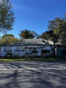 a white building with a fence in front of a street at Coffs Coastal Cabin, Central & Convenient in Coffs Harbour +4 photos