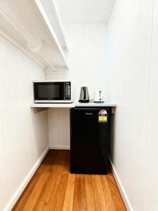 a kitchen with a microwave and a black refrigerator at Coffs Coastal Cabin, Central & Convenient in Coffs Harbour