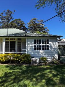 a white house with a green yard at Coffs Coastal Cabin, Central & Convenient in Coffs Harbour