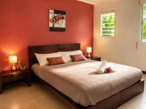 a bedroom with a large bed with red walls at Le Nid de Magenta by Gérald Appartement Premium Magenta Terrasse Parking in Noumea