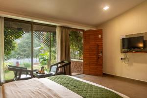 a bedroom with a bed and a tv and a window at Green Nest Resorts in Malebennūr