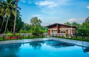 a villa with a swimming pool in front of a house at Green Nest Resorts in Malebennūr