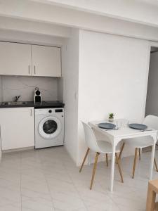 a white kitchen with a table and a washing machine at Cosy T1 Bis climatisé in Toulouse +2 photos
