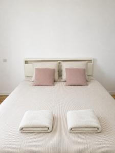 a white bed with two pink pillows on it at Cosy T1 Bis climatisé in Toulouse