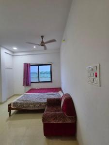 a bedroom with a bed and a couch and a window at Serene Farmhouse in Nimarkheri
