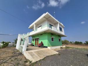 a small green and white house with a sky at Serene Farmhouse in Nimarkheri