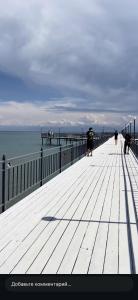 a pier with people walking on it next to the ocean at Townhouse Atlantis Resort in Chetkoysu