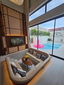 a living room with a large couch and a pool at Villa Mar Pool Villa in Sathani Hat Yai