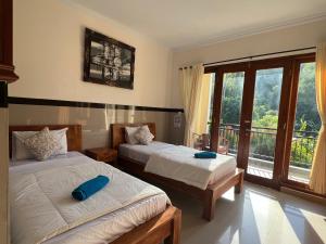 a bedroom with two beds and a balcony at Kailash Homestay in Padangbai