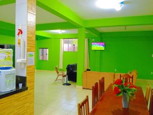 a dining room with green walls and a table with flowers at Araçagy Casa Mar in São José de Ribamar